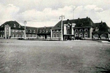 Plac Dworcowy w latach 20 tych, Roślinność jeszcze niska, komin w prawym skrzydle jeszcze niski, ulice i chodnik wybrukowane.